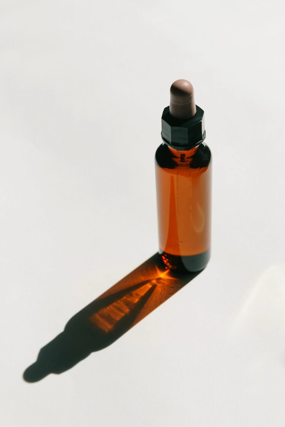 The amber bottle on a white table, its long shadow falling across the morning light